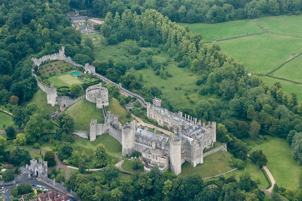 Arundel Castle and its grounds from the air, surrounded by West Sussex woodland.